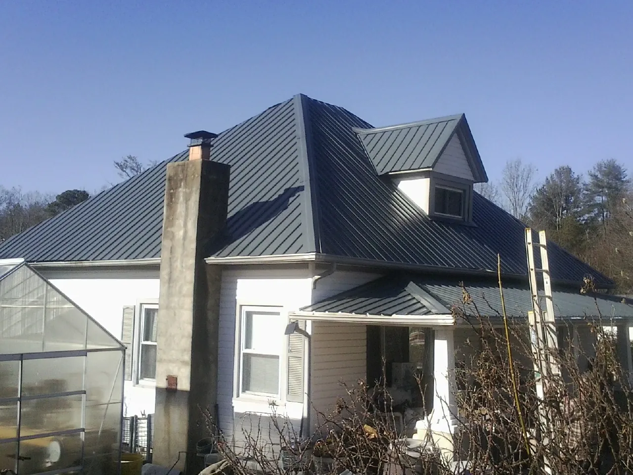 Dark blue standing seam metal roof on a white farmhouse with dormer — Slate & Tile Roof Repair by Roofing Brothers in Vina