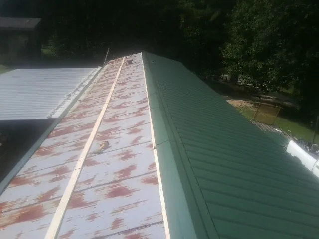 Old rusted panels beside newly installed green metal roofing — Wind Damage Roof Repair by Roofing Brothers in Vina