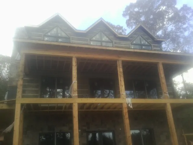 Dormers and porch framing on a large log home under construction — Roof Coating work by our crew in Vina