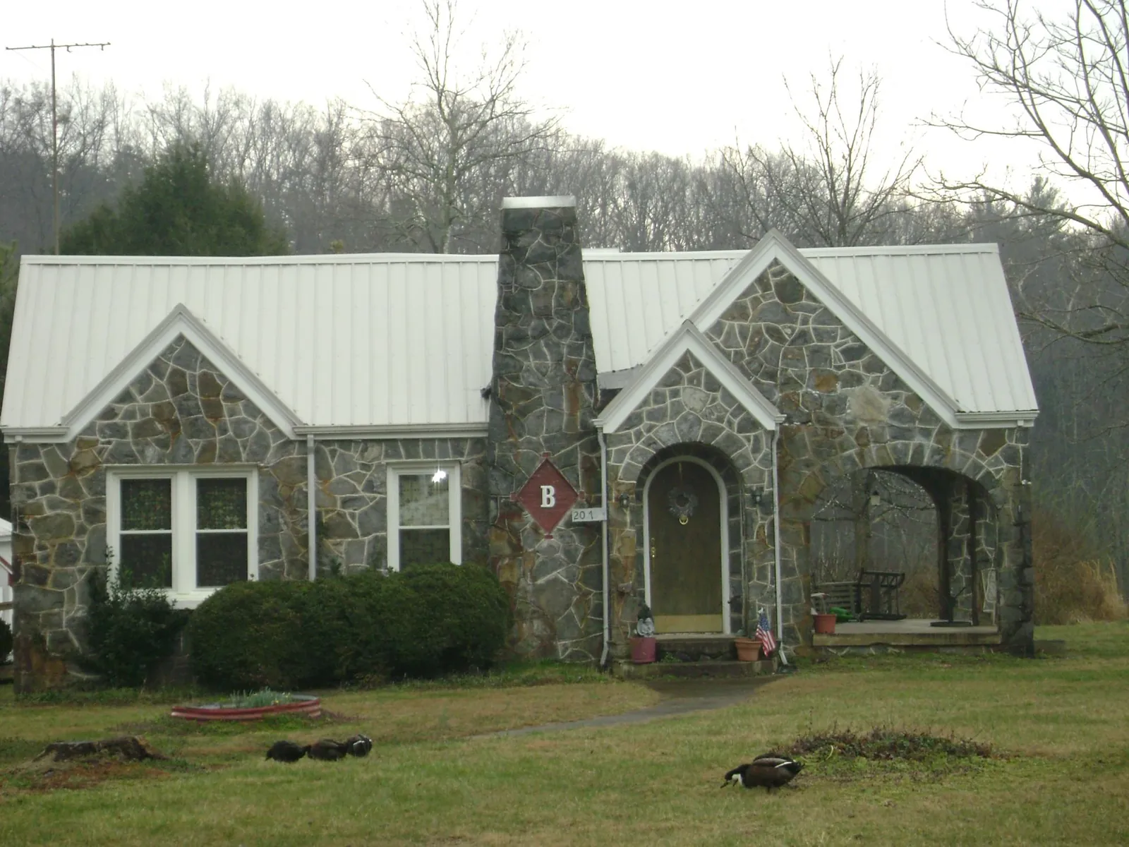 White metal roof on a stone cottage with steep gables in Vina