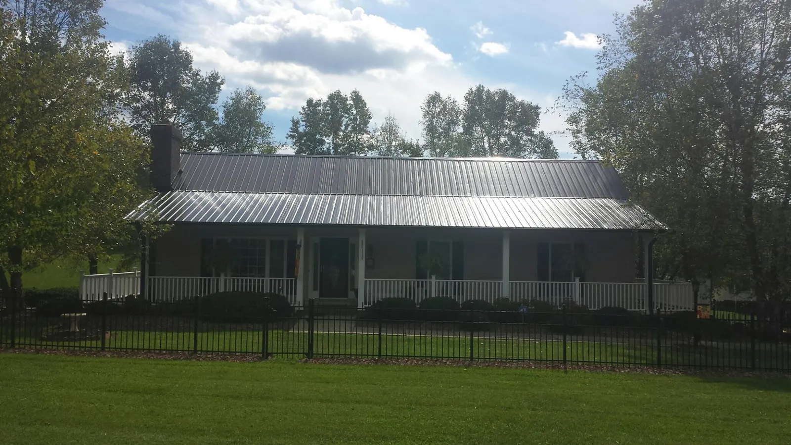 Gray metal roof on a brick ranch with a full width front porch — Gutter Guard Installation work by our crew in Vina