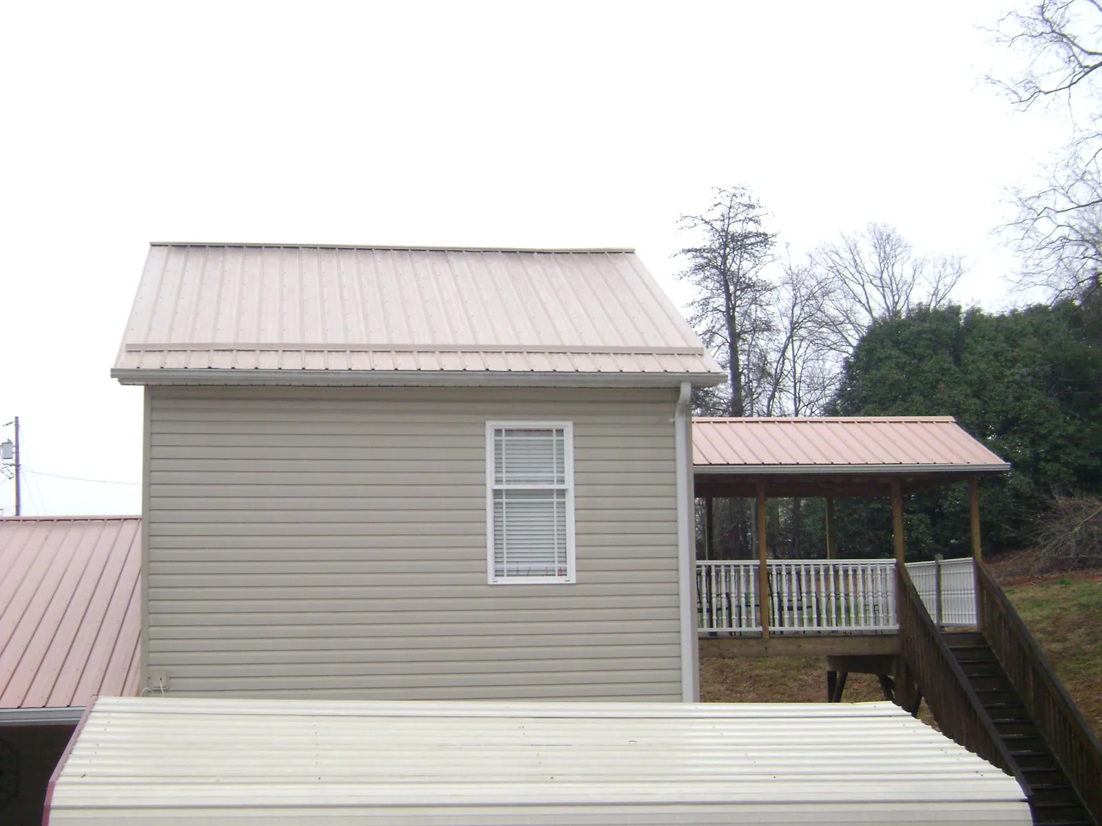 Tan metal roofs on a two story addition and attached porch, from a Roof Replacement job in Vina