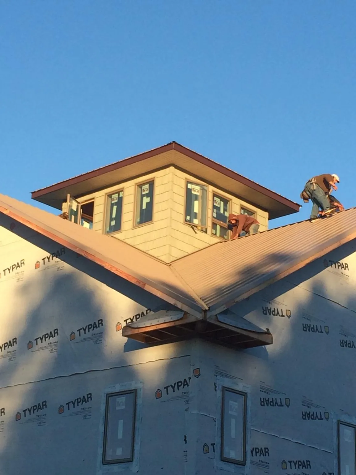 Roofers working around a rooftop cupola on a new metal roof at sunset — Roof Waterproofing in Vina by Roofing Brothers